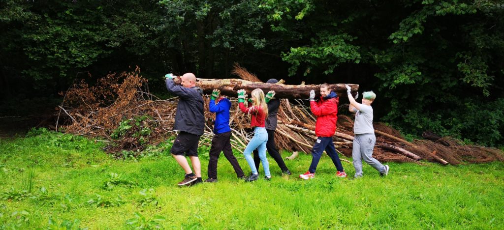 A group of children and a man carrying a wooden log