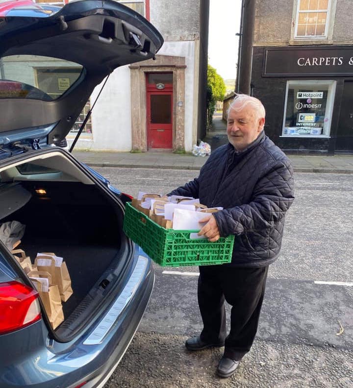 Man holding a tray of vegetables near a car