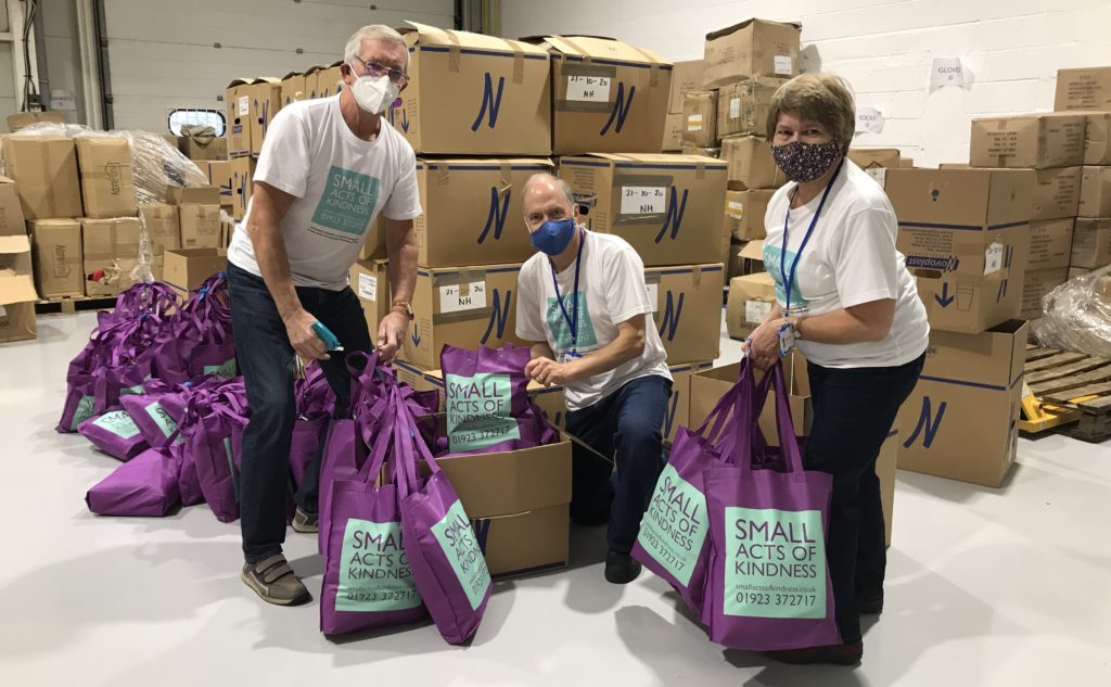 Three people holding small acts of kindness bags