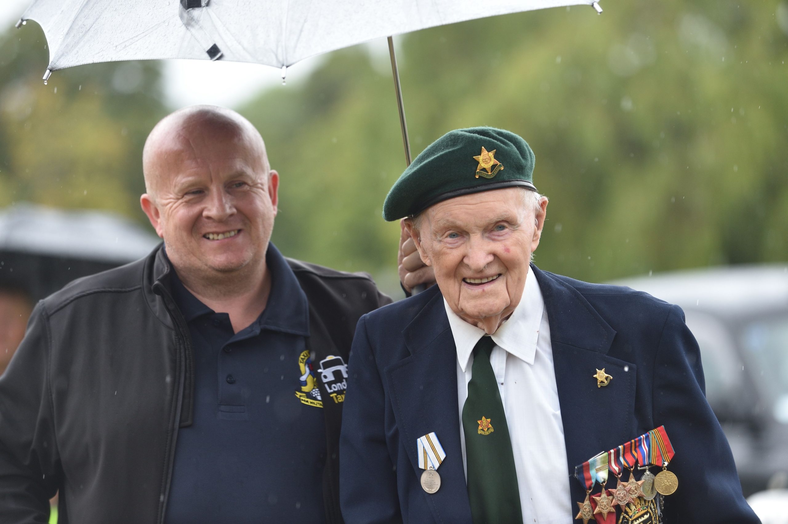 Military veteran and a volunteer holding an umbrella