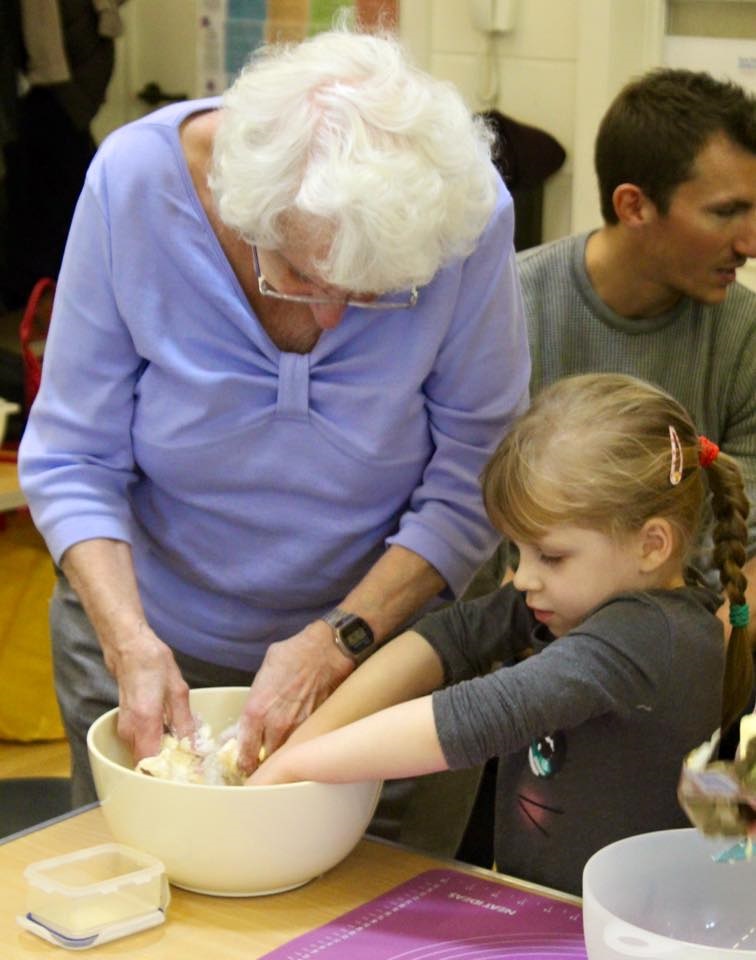 An elderly lady baking with a child