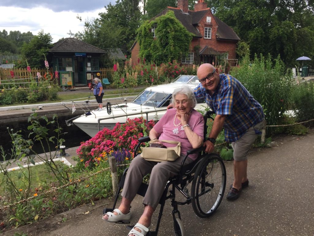 A man pushing a lady on a wheelchair by the canal