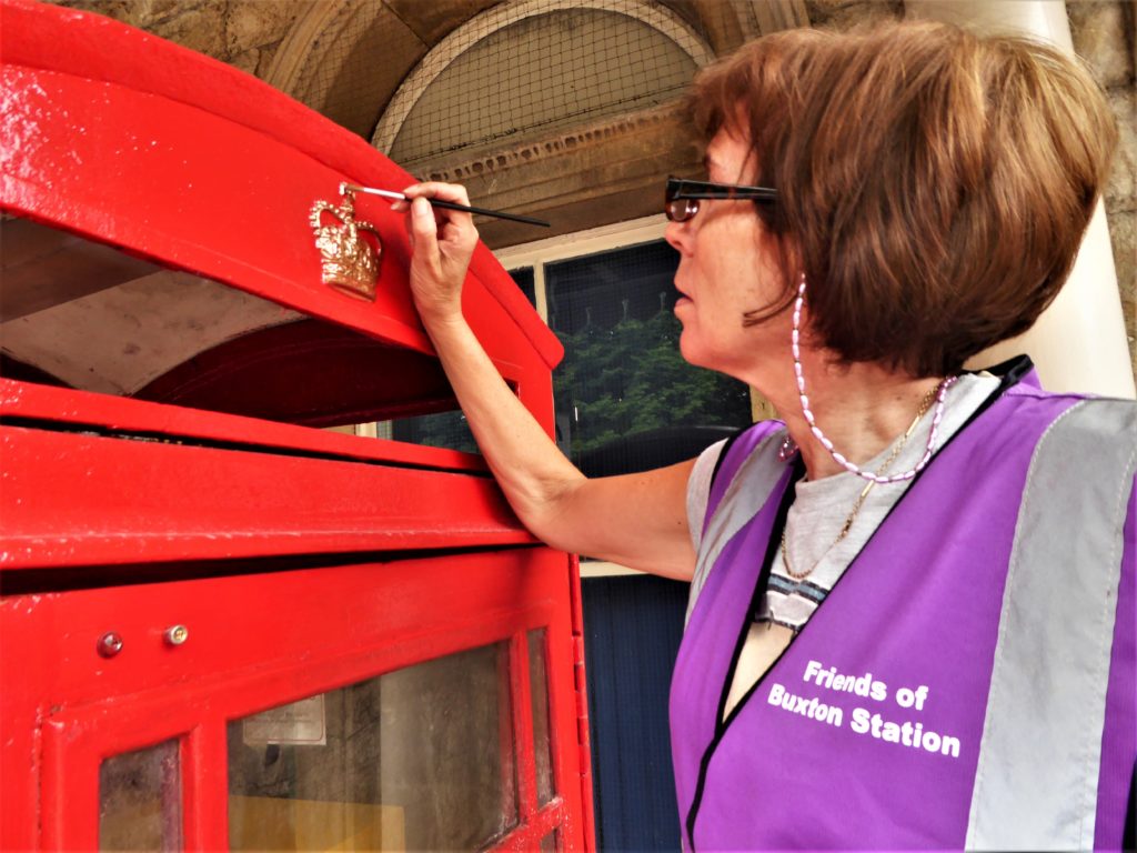 Sue Mellor painting gold crown on red rescued telephone box