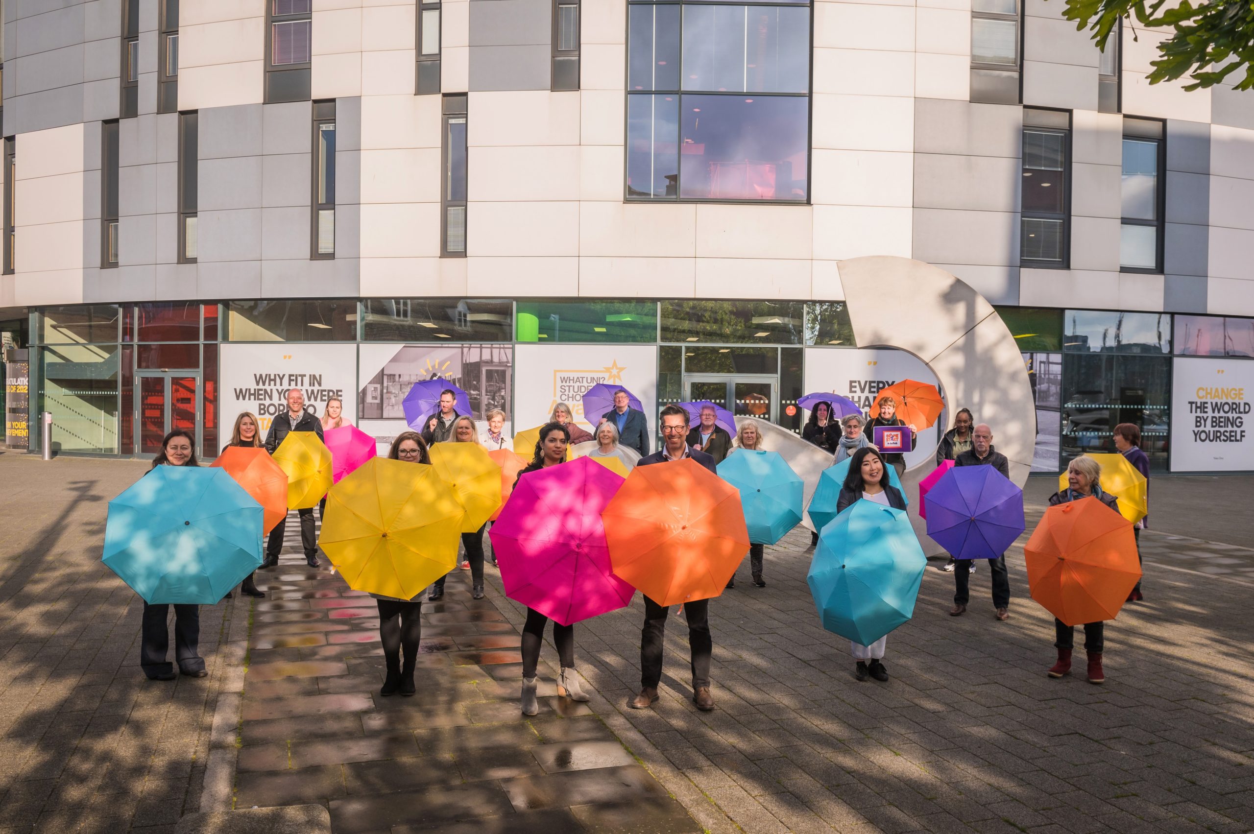 A group of people stood holding colourful umbrella's